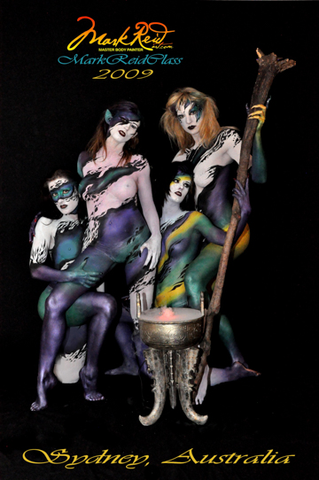 Four women painted in a fashion resembling witches around a cauldron